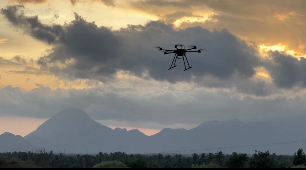 Multirotor drone flying at dusk for stability testing against mountain silhouette