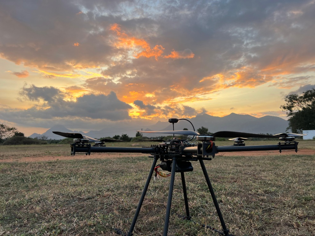 Close-up of a carbon fiber research drone sitting on grass in field at sunset